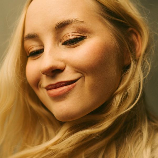 Content woman's portrait with a gentle, peachy glow.